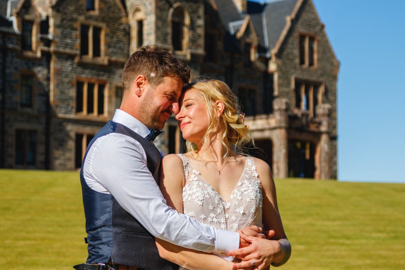 Couple just married holding each other in front of castle.A Highland sunny wedding Duncraig castle