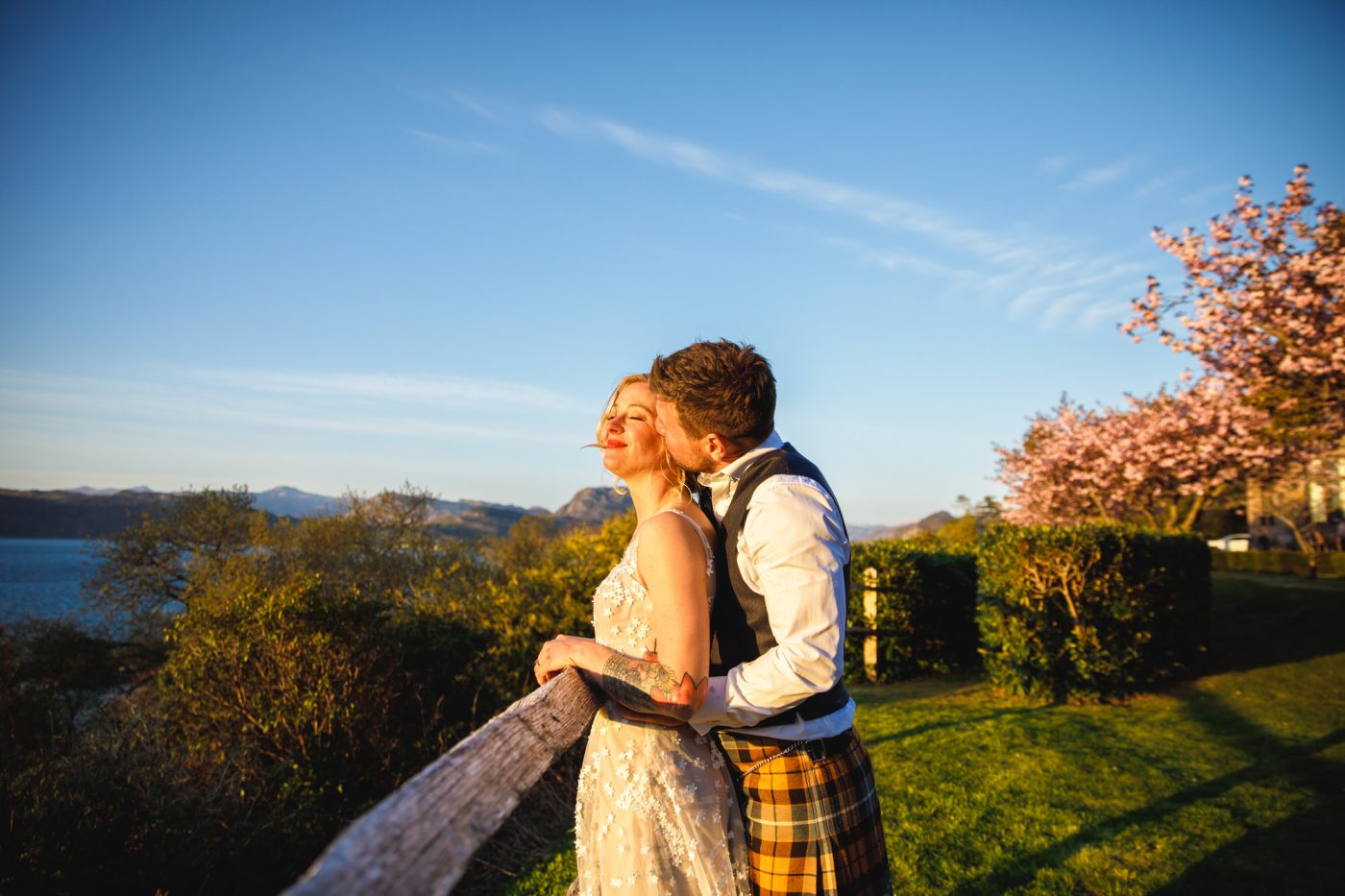 And holding lady from behind with blue sky and a cherry blossom tree