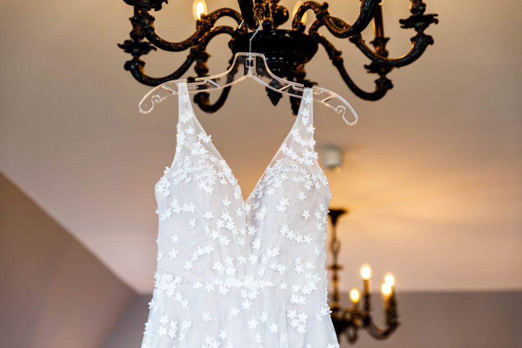 wedding dress hung from chandelier with daisies