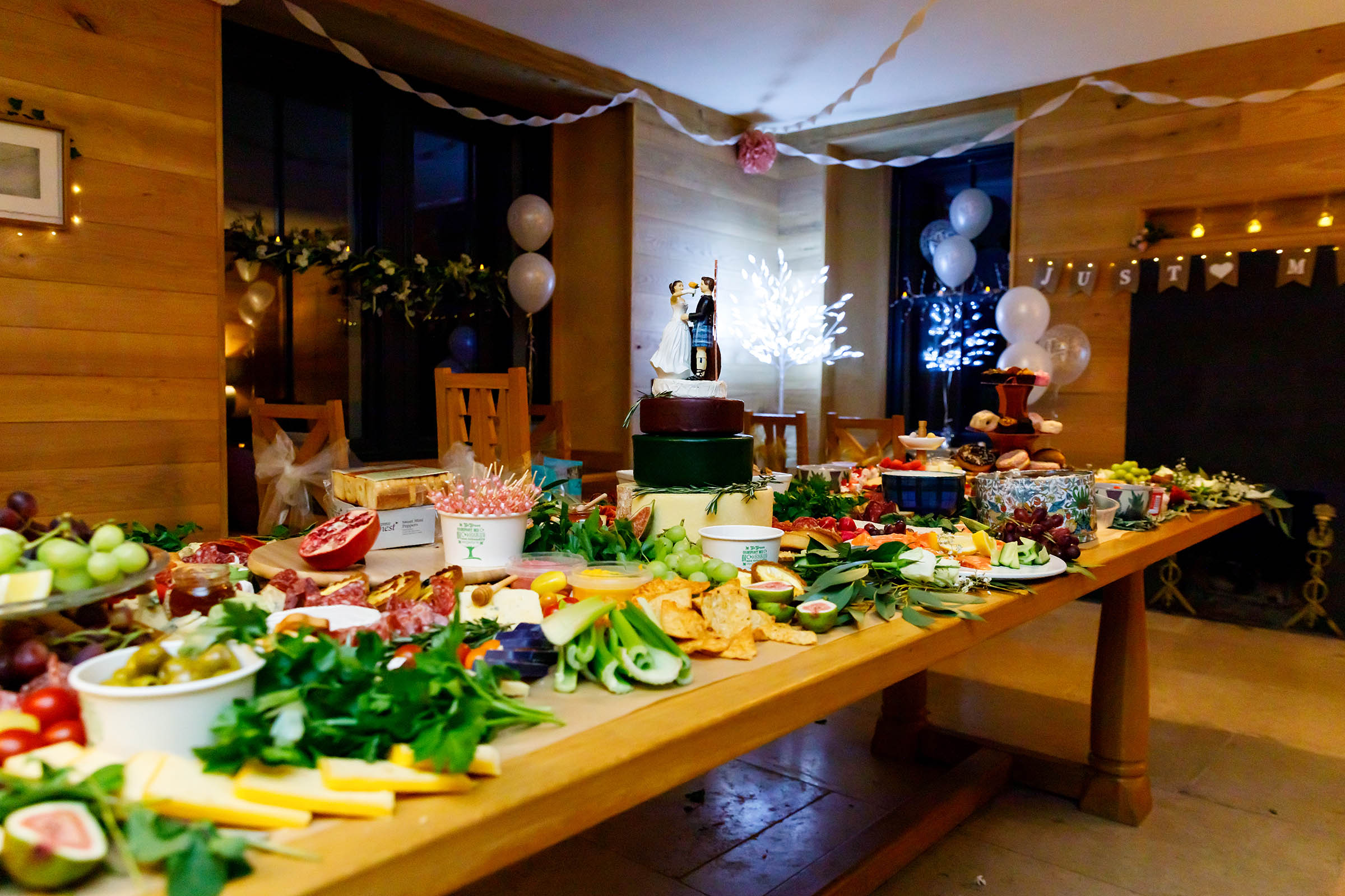 grazing table full of cheese , salami grapes and a cheese wedding cake