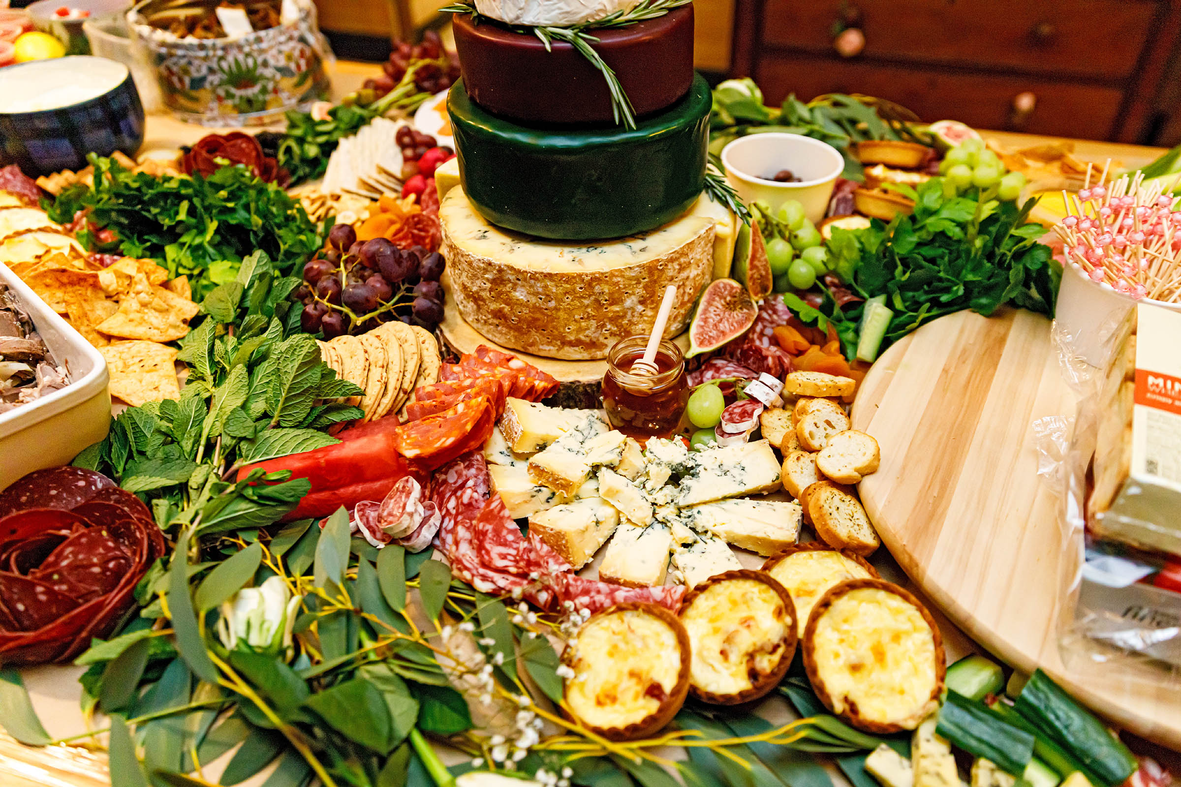 grazing table full of cheese , salami grapes and a cheese wedding cake