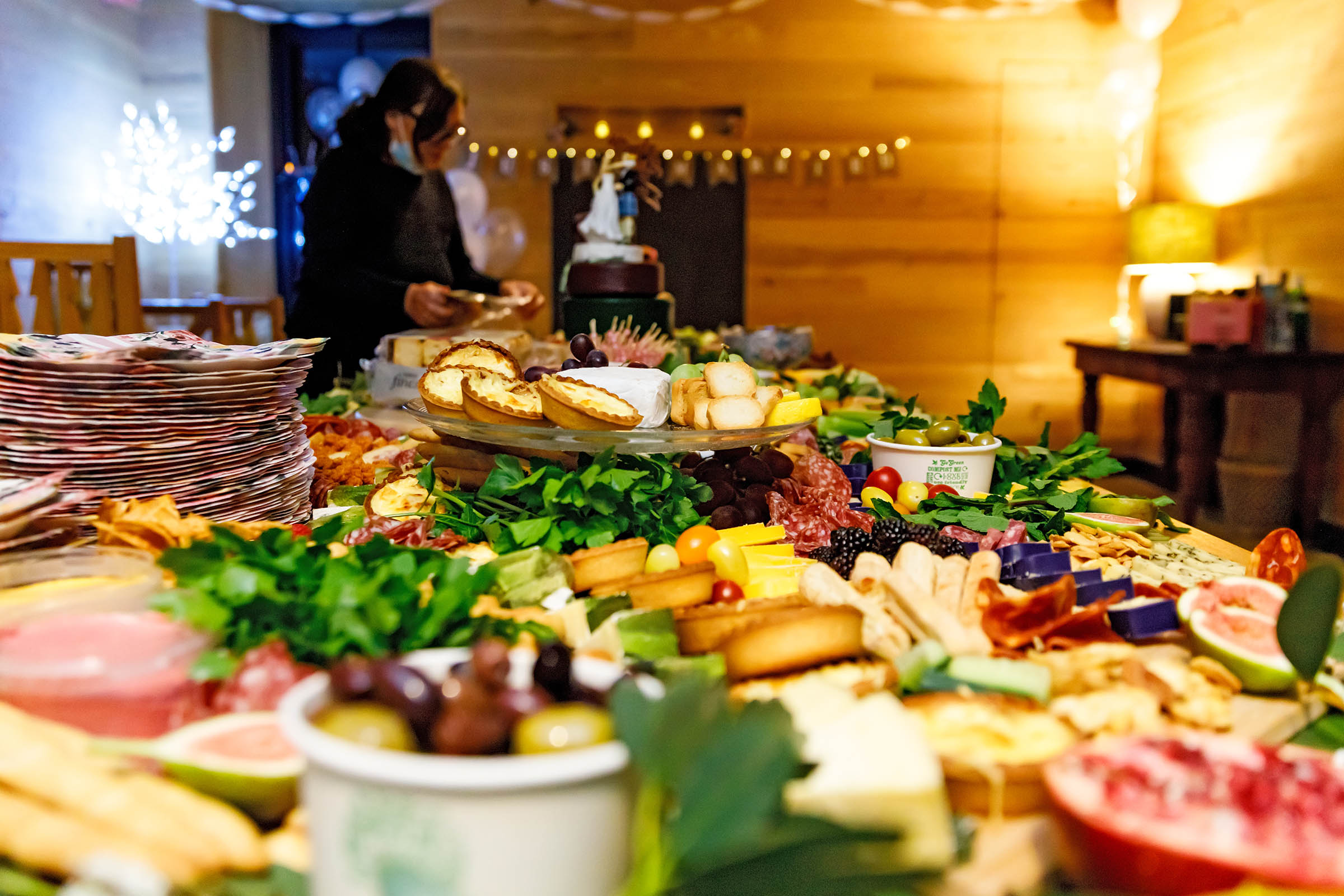 grazing table full of cheese , salami grapes and a cheese wedding cake